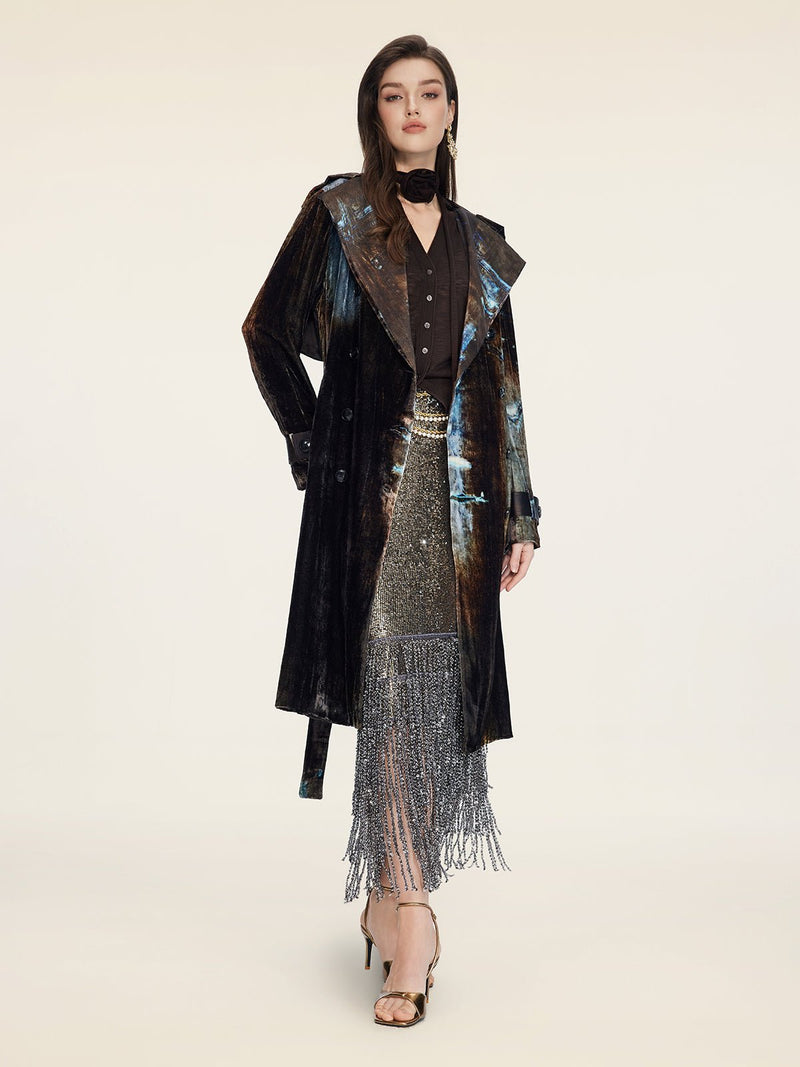 A woman poses in a studio wearing the Social Queen Velvet Gradient Tie-Waist Trench Coat, styled with a black blouse, metallic fringe skirt, and gold heels against a neutral background.