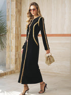 A woman in the Social Queen Velvet Jewel-Trim Dress, holding a textured beige handbag and wearing sunglasses and heels, stands indoors by a stone wall.