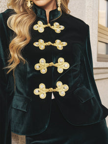 Close-up of a person wearing the Social Queen Velvet Knot-Button Jacket—an emerald velvet blazer with ornate gold knot buttons—making it a stylish choice for wedding guests.