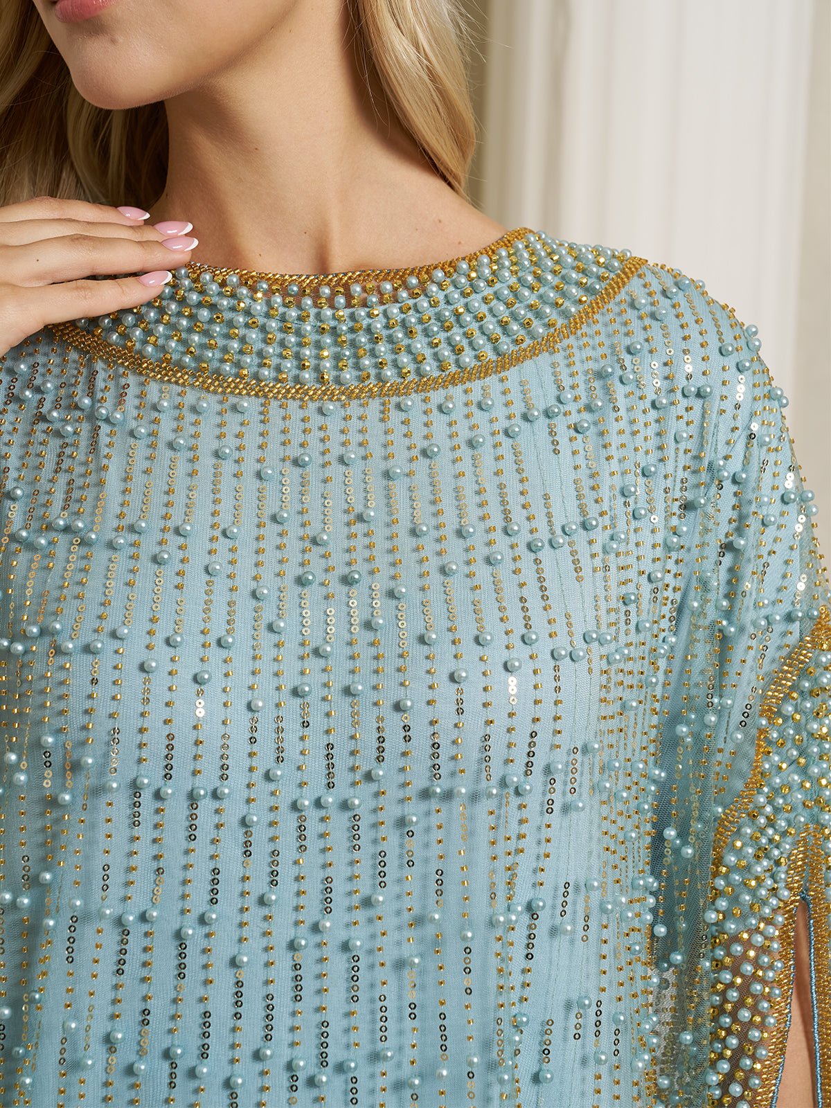 A woman wearing the Social Queen Vertical Beaded Double-Layer Caftan Dress in light blue, featuring rows of pearls and gold beading, with her hand near the collar.