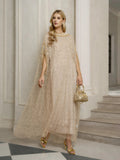 A woman stands indoors in a Social Queen Vertical Beaded Double-Layer Caftan Dress with gold heels and a matching handbag, near a staircase and white columns—stylishly ready for any celebration.