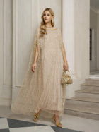 A woman stands indoors in a Social Queen Vertical Beaded Double-Layer Caftan Dress with gold heels and a matching handbag, near a staircase and white columns—stylishly ready for any celebration.