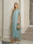 A woman stands indoors wearing the Social Queen Vertical Beaded Double-Layer Caftan Dress in light blue with gold accents, holding a small gold bag and pairing it with floral high-heeled sandals.