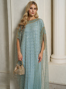 A woman wears the Social Queen Vertical Beaded Double-Layer Caftan Dress in light blue, standing indoors with a gold handbag, white columns, and a textured wall in the background.