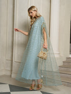 A woman in a light blue Social Queen Vertical Beaded Double-Layer Caftan Dress holds a gold handbag and stands near a column on a staircase.