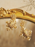 Vintage Embossed Earrings by Social Queen feature intricate leaf patterns and gold plating, resting elegantly on a decorative mirror—ideal wedding guest jewelry for lovers of timeless style.