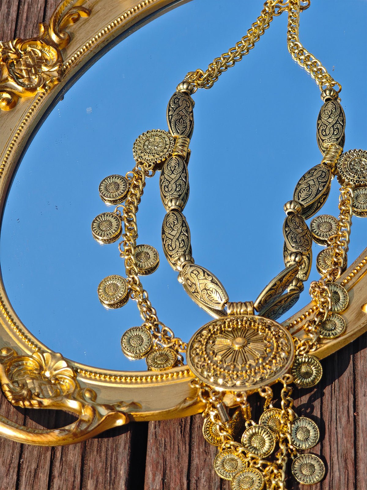 The Social Queen Vintage Sunflower Necklace is displayed on a decorative oval gold-framed mirror, set elegantly on a wooden surface.